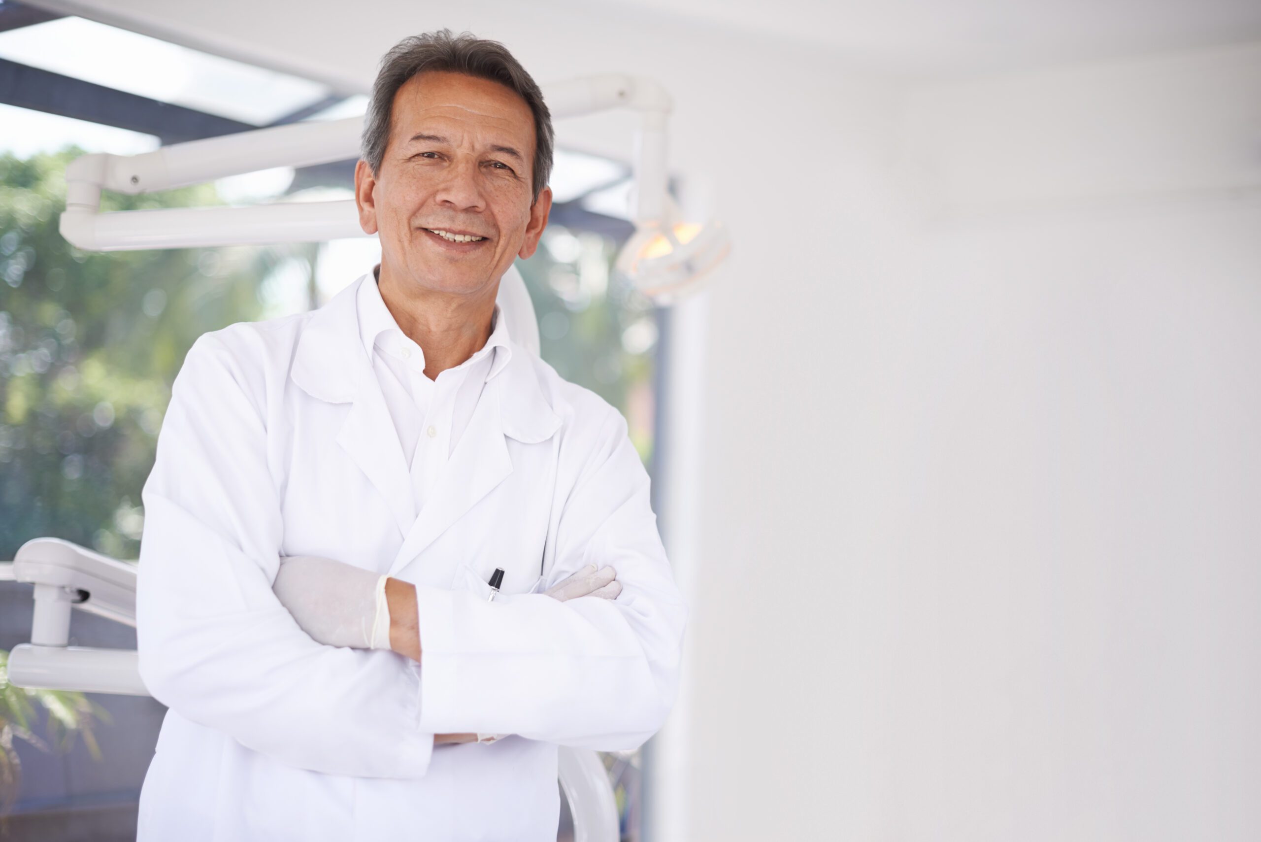 dentista professionista in camice bianco con braccia conserte: esempio di libero professionista che ha fatto la Diagnosi dei Rischi per proteggere il proprio studio e patrimonio personale
